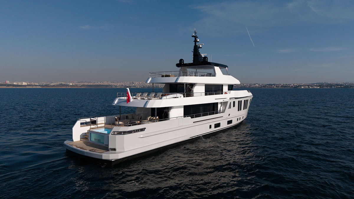 BEE YACHTS 35M EXPLORER yacht sailing on calm blue sea under clear sky, viewed from the rear side showing multiple decks and outdoor lounging areas
